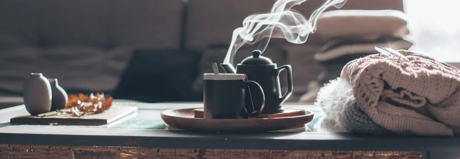 Dampfende Teekanne und Tasse auf einem Tisch